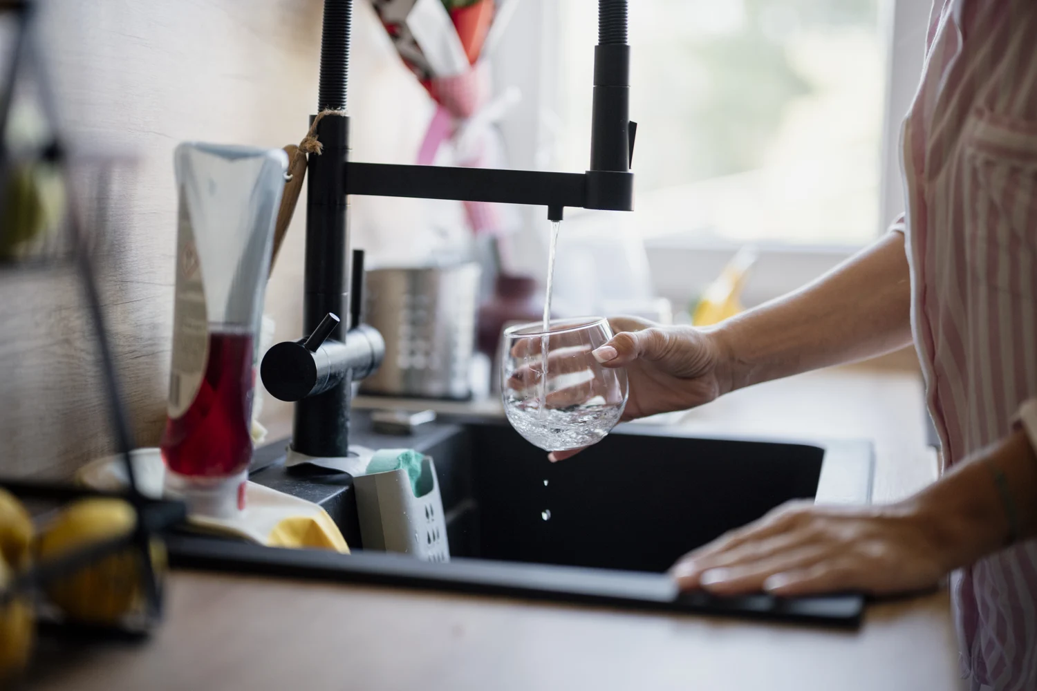 Wasser fließt aus einem Küchenhahn in ein Glas